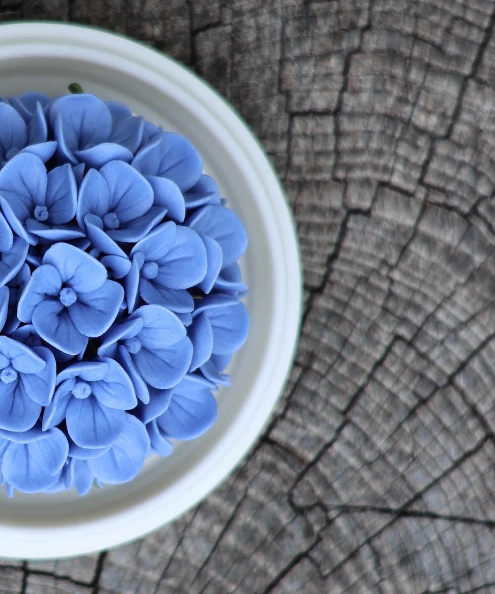 Hand-pinched porcelain flower diffuser with essential oil bottle, showcasing the cold diffusion process for a smokeless home fragrance experience.