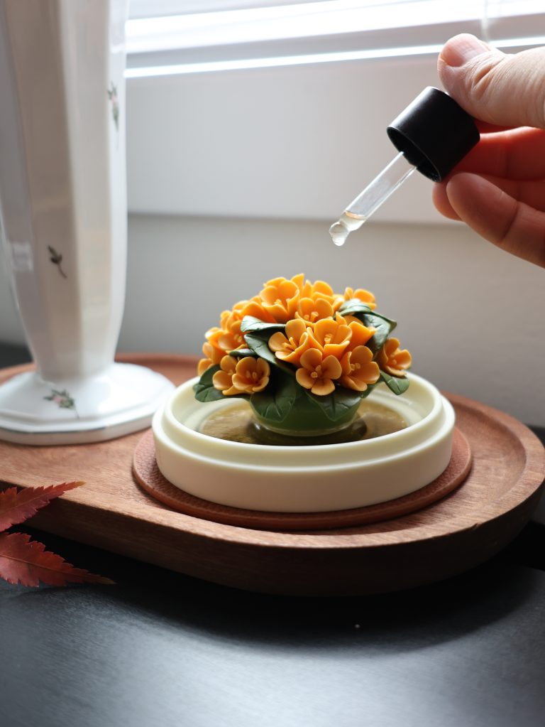 Hand-pinched porcelain Osmanthus bloom diffuser with essential oil bottle, showcasing smokeless home fragrance in a modern interior.